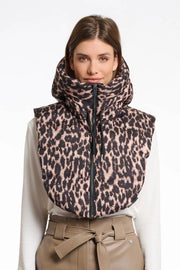 Woman wearing a leopard print vest over a white shirt and beige pants on a white background