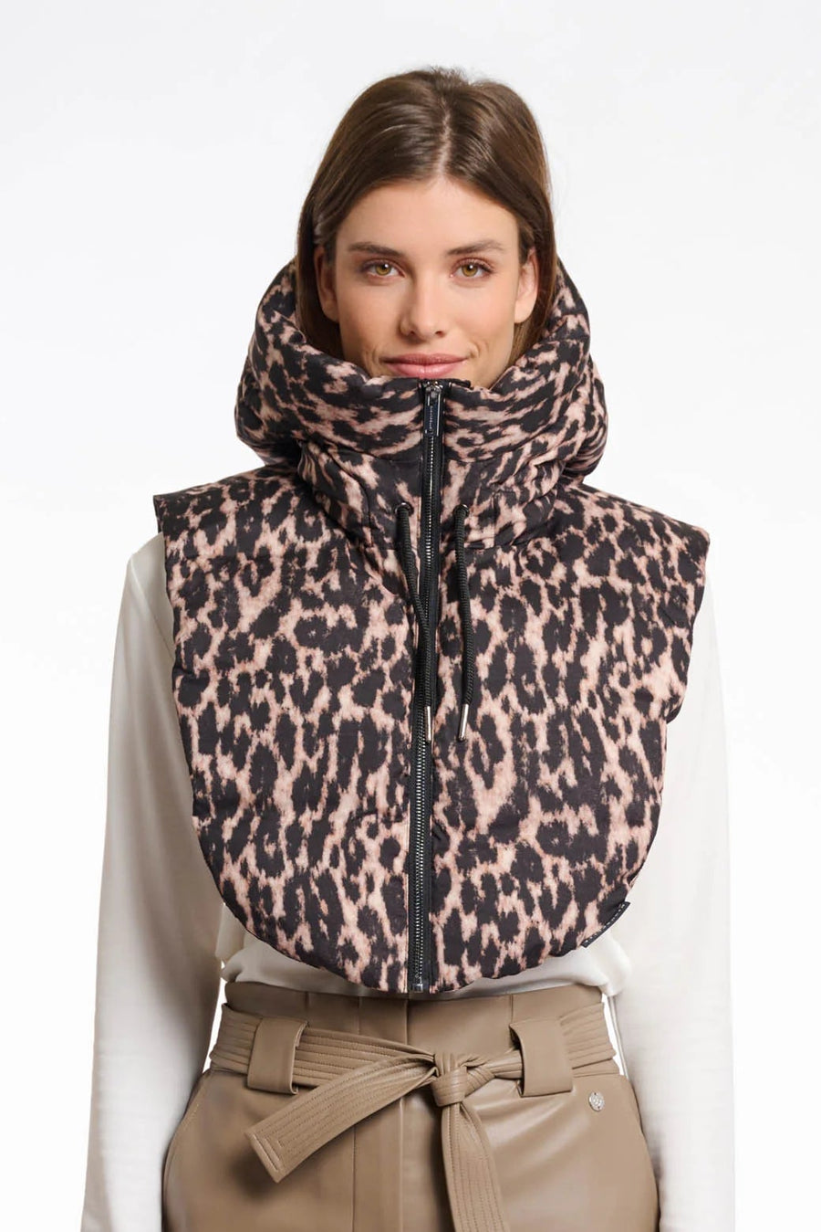 Woman wearing a leopard print vest over a white shirt and beige pants on a white background