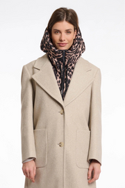Woman wearing a beige coat and a patterned collared hood on a white background