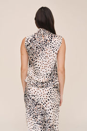 women wearing a white sleeveless cowl neck top with brown and black print 