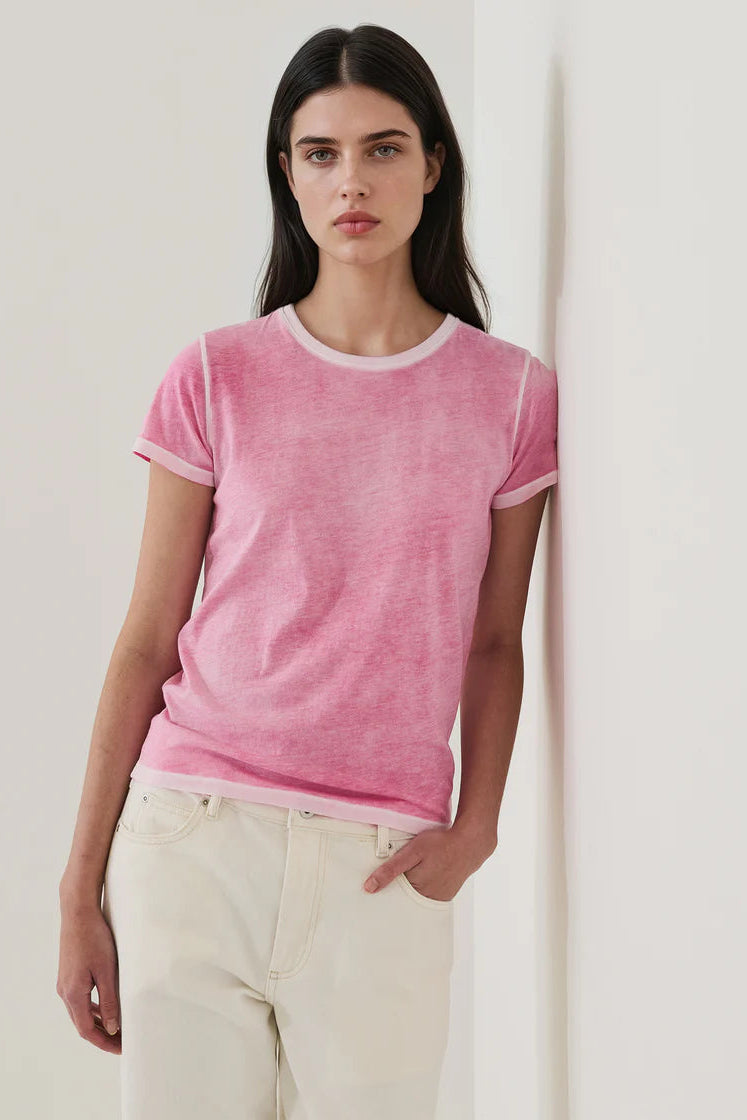 woman wearing a pink short-sleeve crewneck t-shirt with contrast trim paired with light-colored pants, front