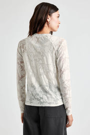 back view of woman wearing an off white lace-like long sleeve