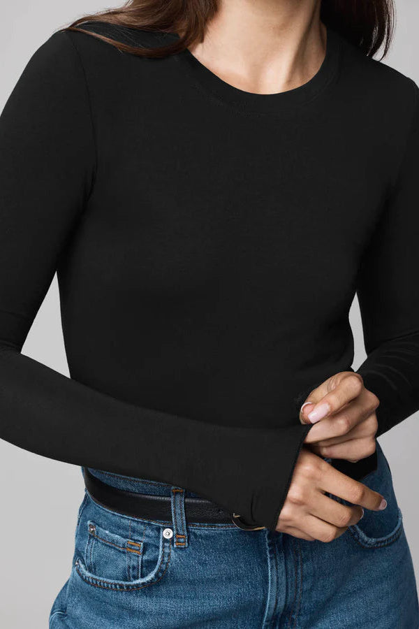 Person wearing a black long-sleeve top and blue jeans on a gray background