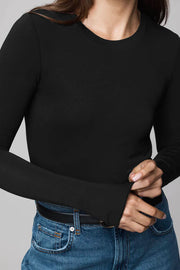 Person wearing a black long-sleeve top and blue jeans on a gray background