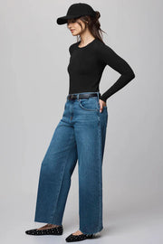Woman wearing a black top and blue jeans on a gray background