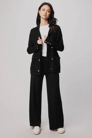 Woman wearing a black suit with a white shirt on a plain background