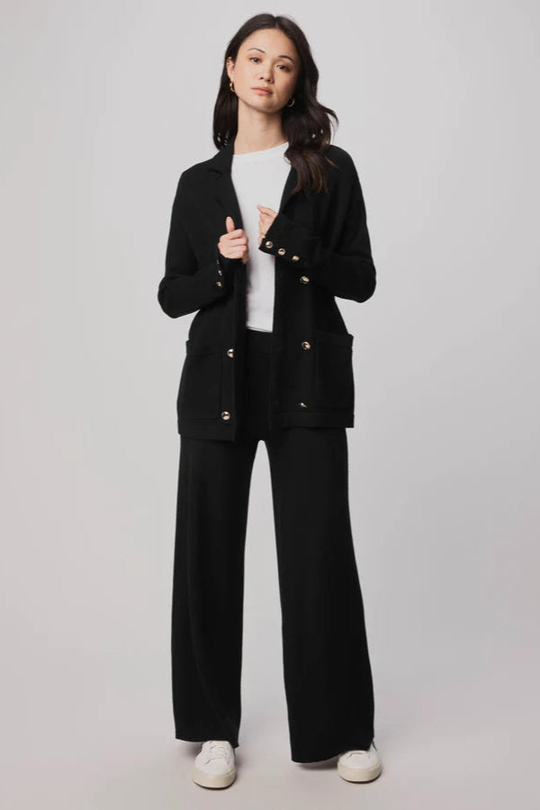 Woman wearing a black suit with a white shirt on a plain background