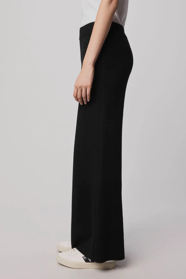 Person wearing black wide-leg pants on a plain background