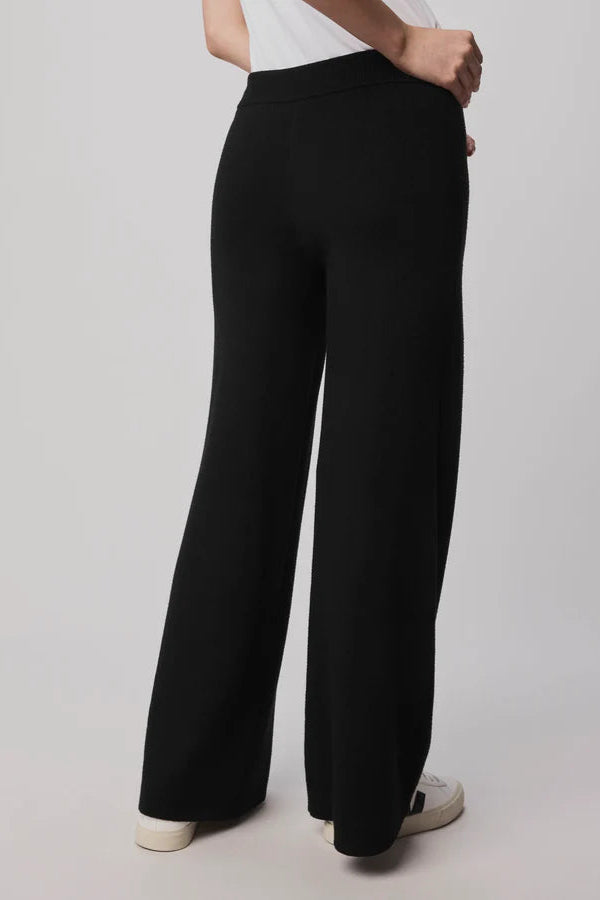 Person wearing black wide-leg pants on a plain background