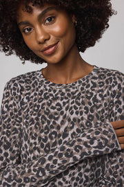 Woman wearing a leopard print sweater against a plain background