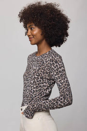 Woman wearing a leopard print top and white pants against a plain background