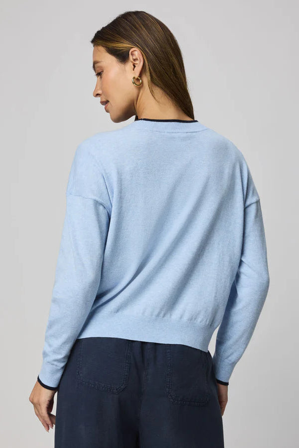 woman wearing a light blue sweater with a navy heart design and "XOXO" embroidered 