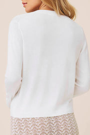 Woman wearing a white long-sleeve button up knit cardigan 