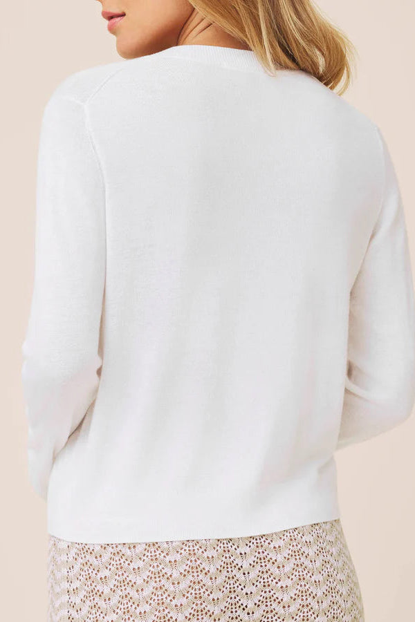 Woman wearing a white long-sleeve button up knit cardigan 