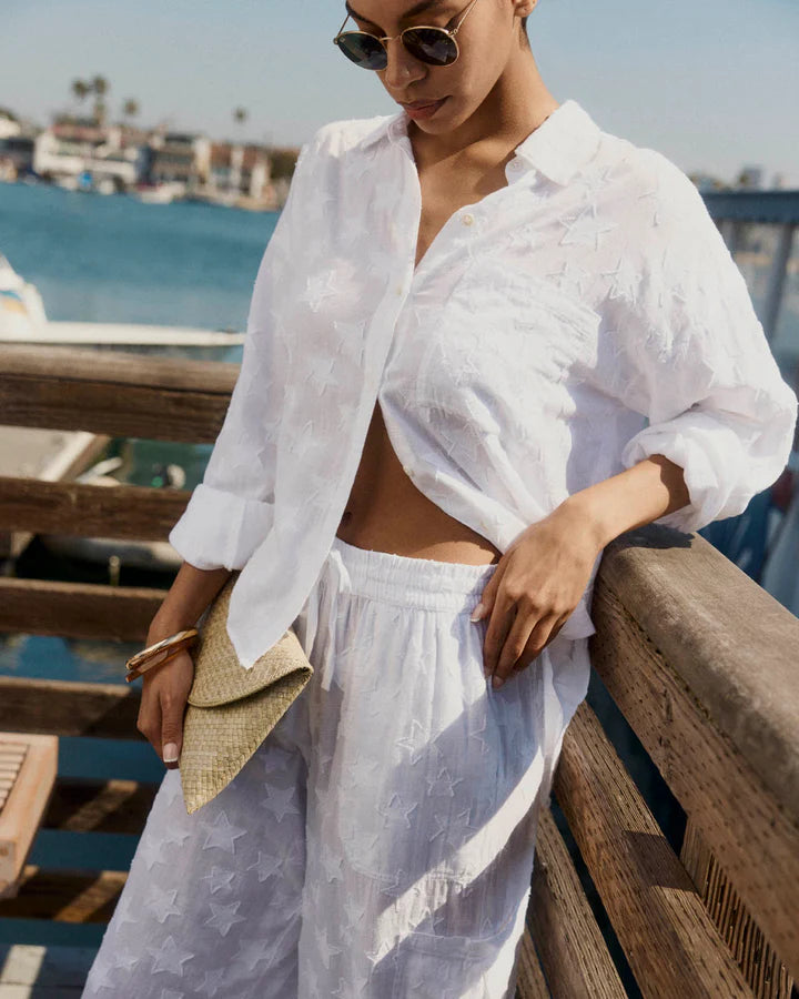 Woman wearing white button up top with star details 