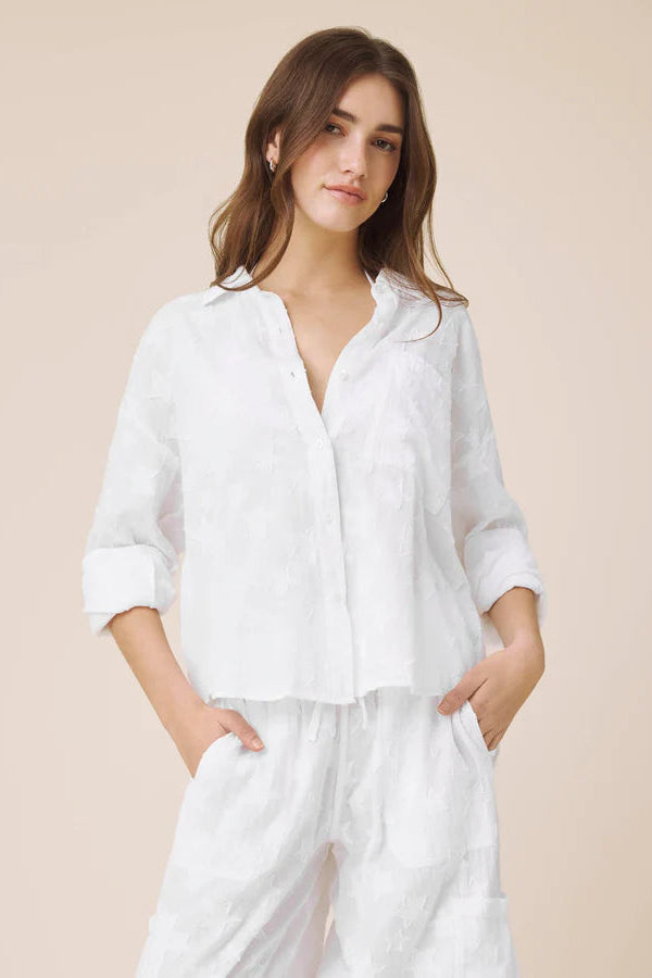 Woman wearing white button up top with star details 