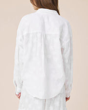 Woman wearing white button up top with star details 