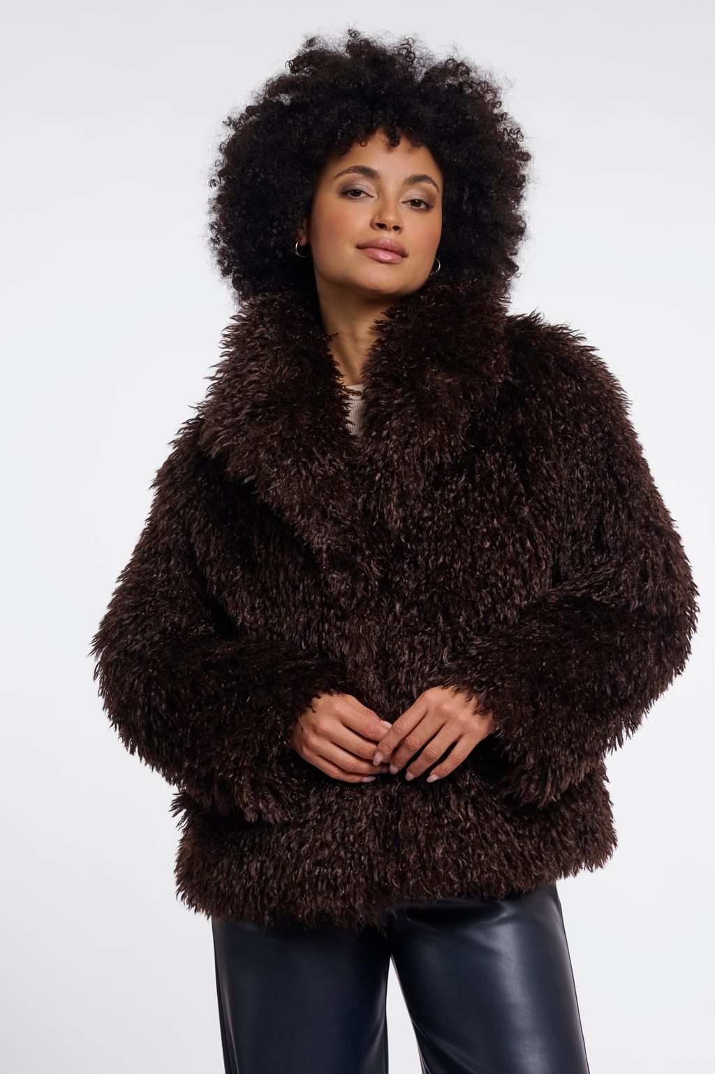 Woman wearing a brown faux fur jacket in chocolate brown. 