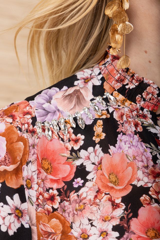 Close-up of the collar of a black background blouse with colourful flowers