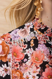 Close-up of the collar of a black background blouse with colourful flowers