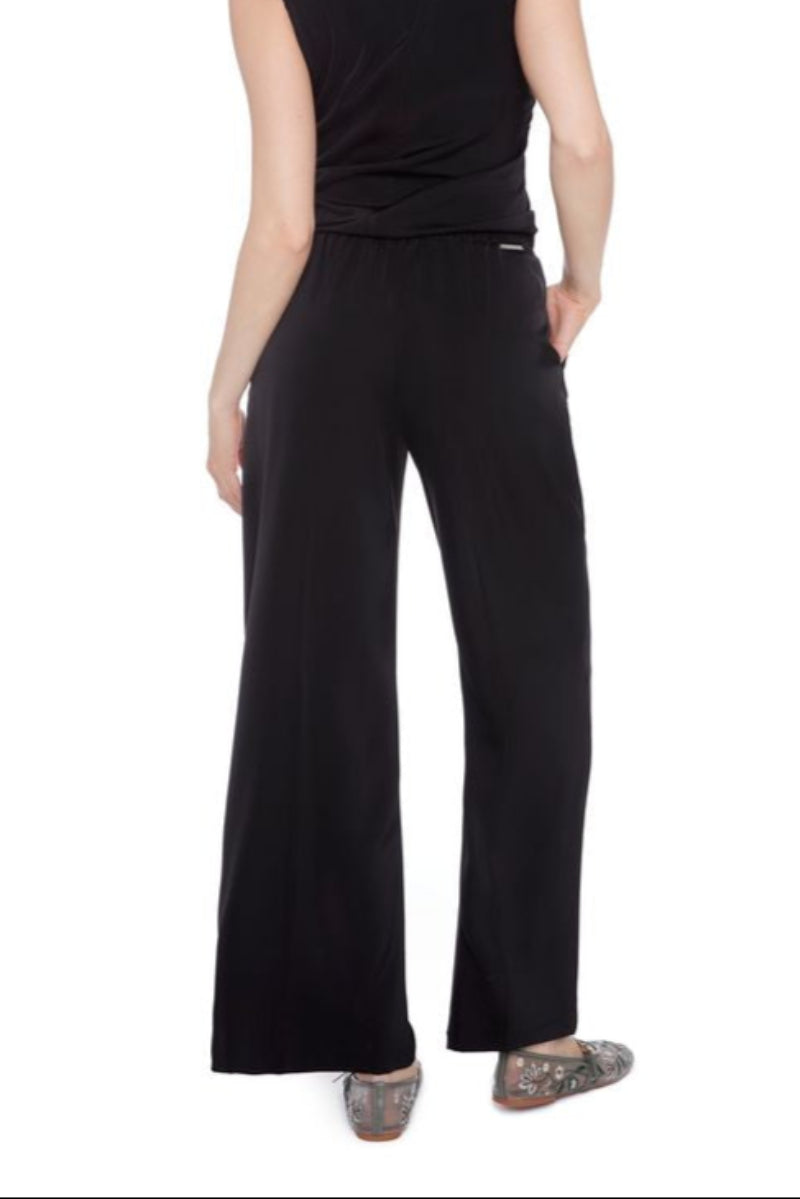 Back view of a woman wearing matching black satin sleeveless top and wide-leg pants on a white background