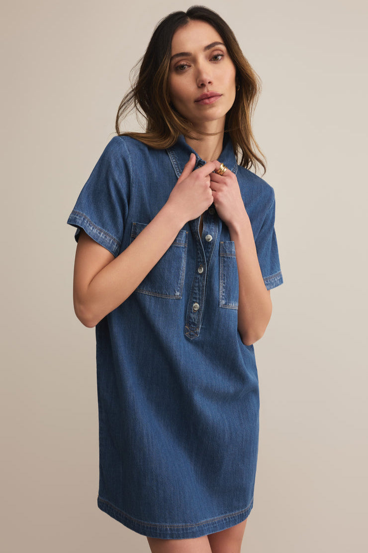Woman wearing a blue denim dress against a beige background