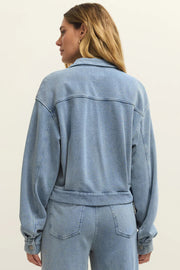 Woman wearing a light blue denim zip-front jacket with chest pockets, back view