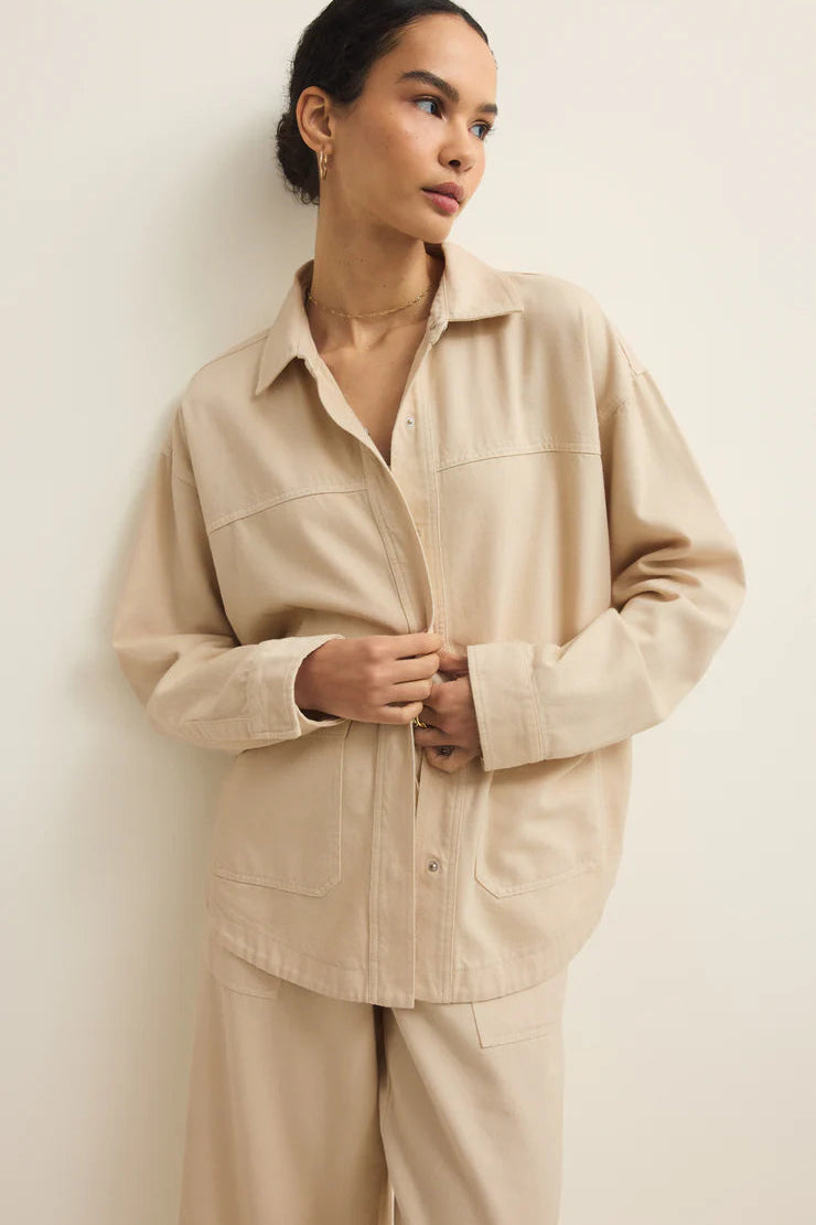 a woman wearing a light beige twill collared button up jacket