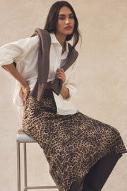 Woman wearing a leopard print scarf and dress against a neutral background