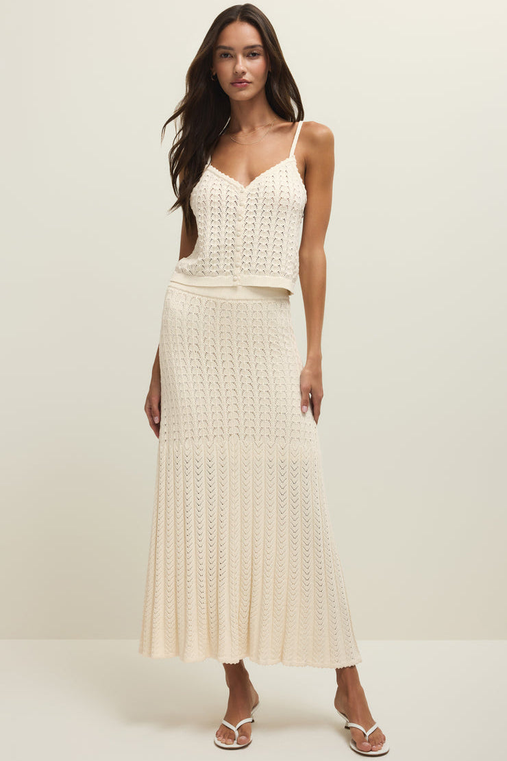 Woman wearing a cream knit midi skirt with elastic waistband and tank top