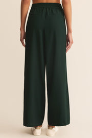 Dark green wide-leg pants worn by a person on a beige background