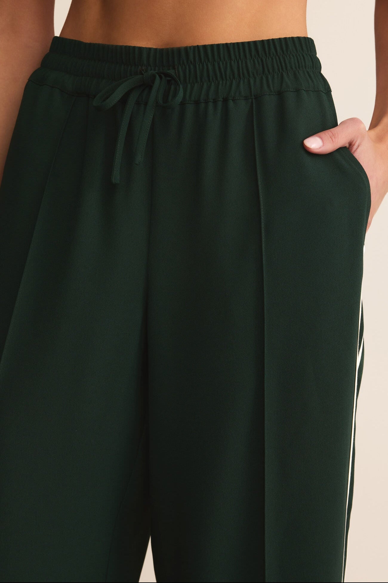 Dark green pants with a drawstring waist on a neutral background