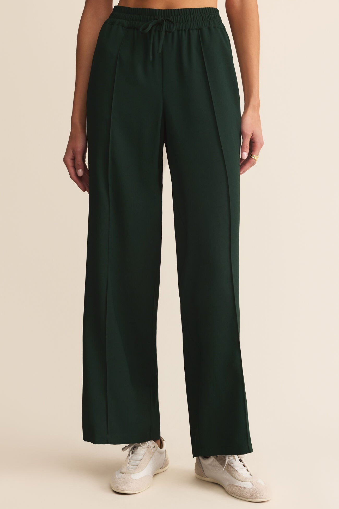 Dark green wide-leg pants worn by a person on a beige background
