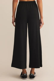 Black wide-leg pants worn by a person on a beige background