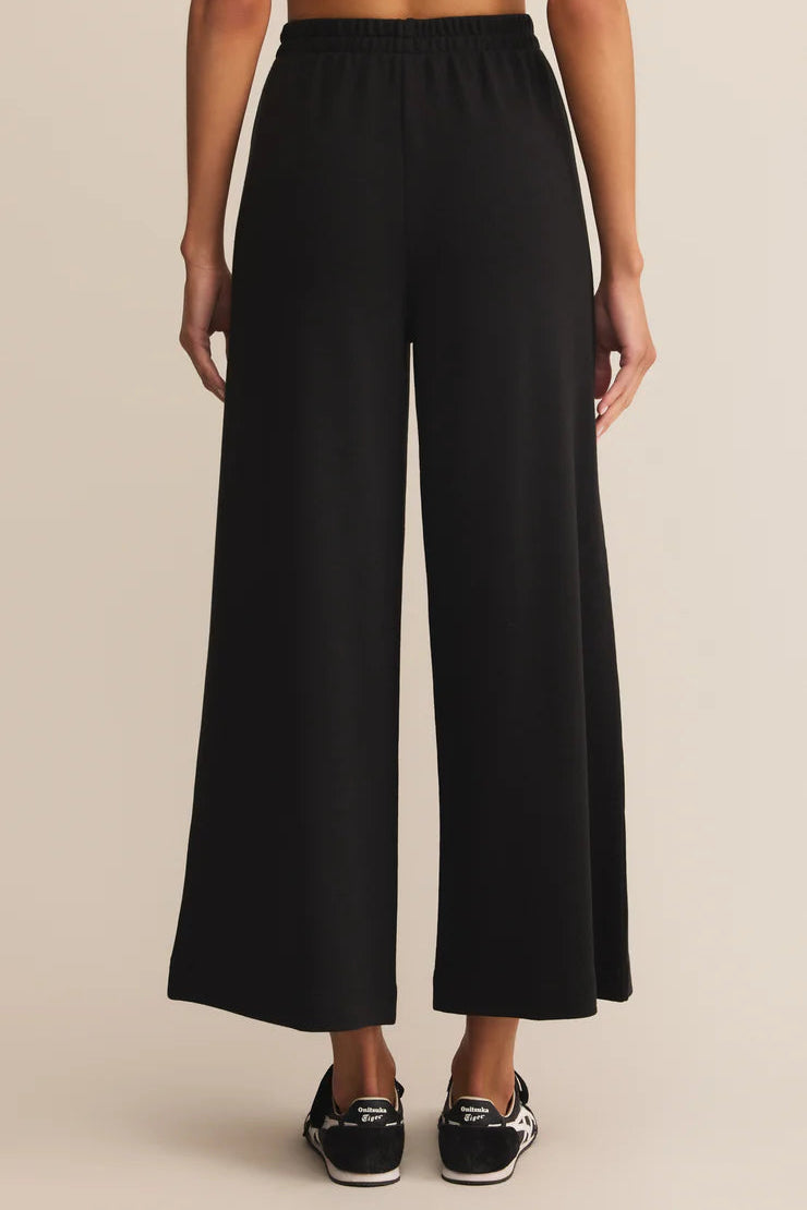 Black wide-leg pants worn by a person on a beige background