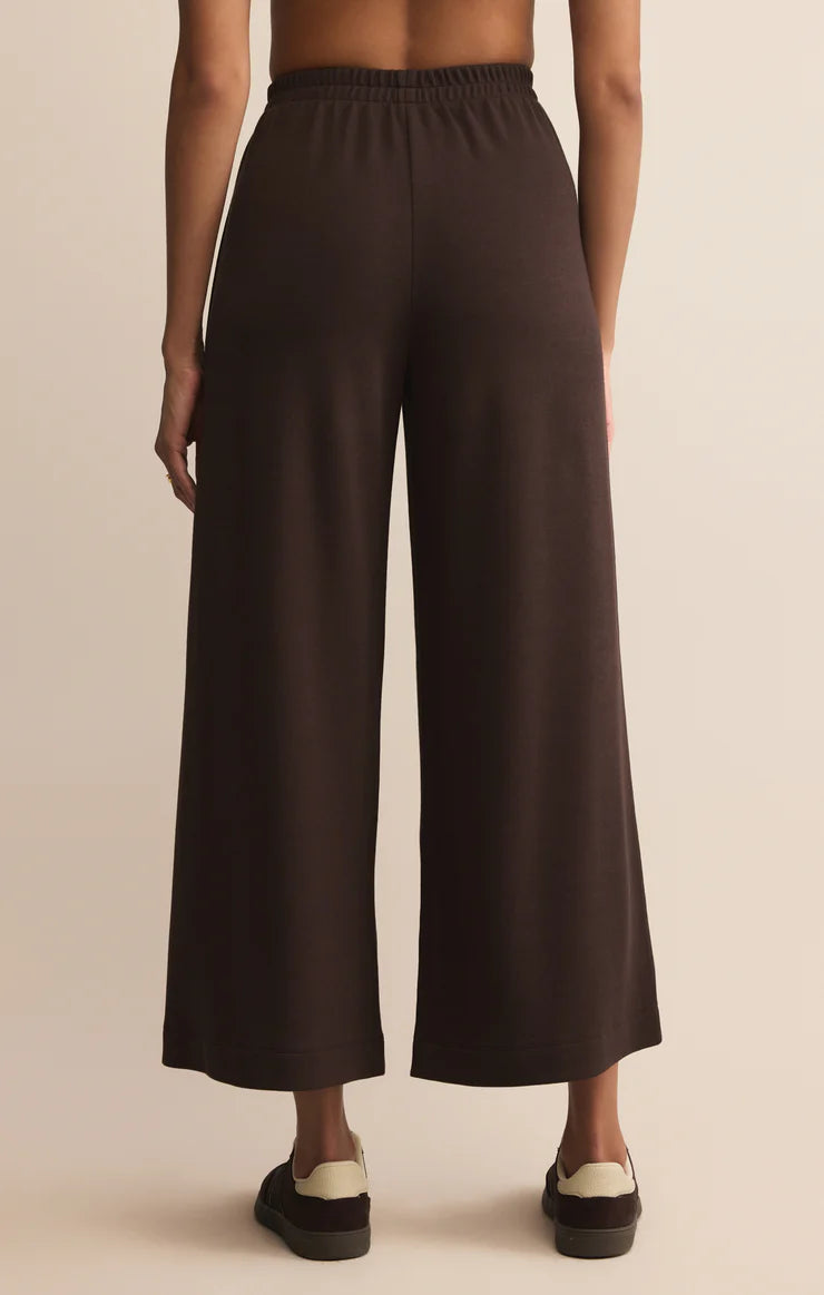 Dark brown wide-leg pants worn by a person on a beige background