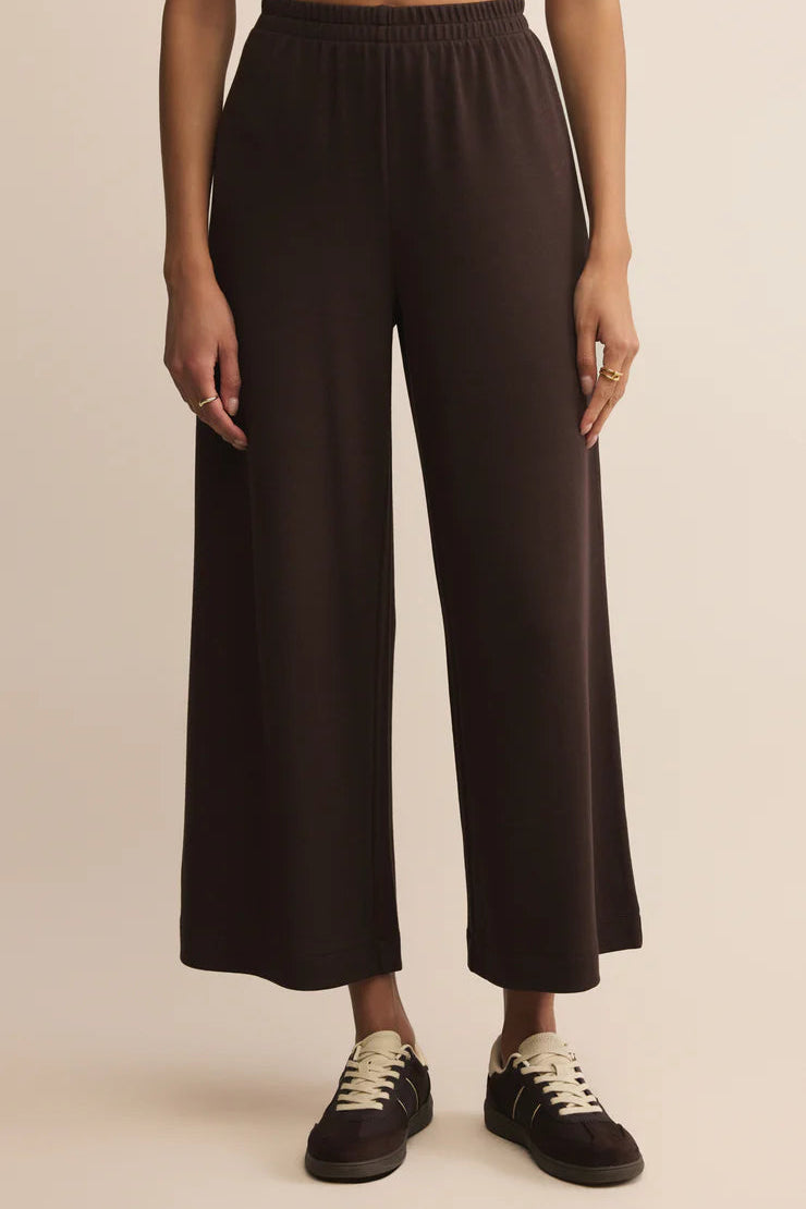 Person wearing brown cropped wide-leg pants on a beige background