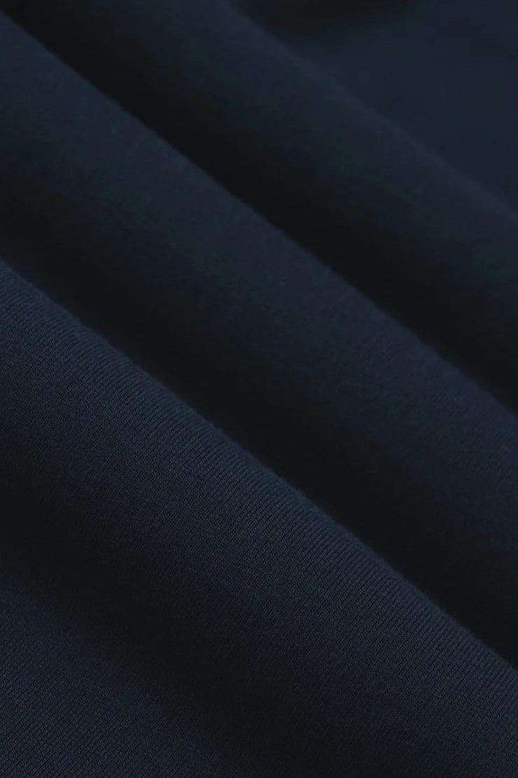 Woman wearing navy wide leg pants with drawstring waistband and contrast white side stripe, fabric detail view