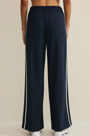 Woman wearing navy wide leg pants with drawstring waistband and contrast white side stripe, back view