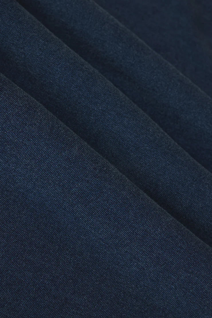 Woman wearing a navy blue denim wash sleeveless v-neck knit tank top with relaxed fit, fabric detail view