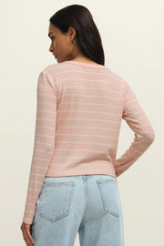Woman wearing a long sleeved pink henley knit top with cream stripes and a button placket, front view