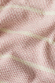 Woman wearing a long sleeved pink henley knit top with cream stripes and a button placket, fabric detail view