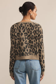 Person wearing a leopard print sweater and blue jeans on a beige background