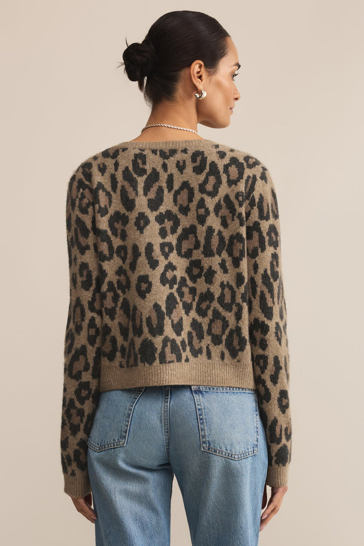 Person wearing a leopard print sweater and blue jeans on a beige background