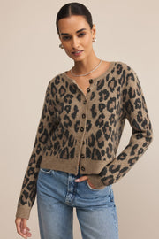 Woman wearing a leopard print cardigan and blue jeans on a beige background