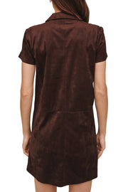A woman viewed from the back wearing a short-sleeve brown velvet dress with a collar and a large back pocket, set against a plain white background.