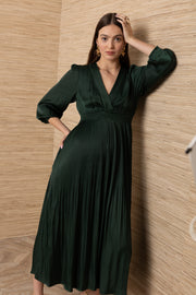 A woman wearing a dark green pleated midi dress with three-quarter sleeves and a V-neckline