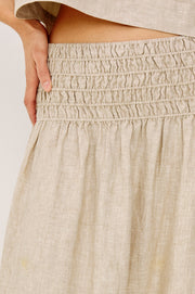 Woman wearing a beige linen midi skirt with a smocked elastic waistband, detaiil