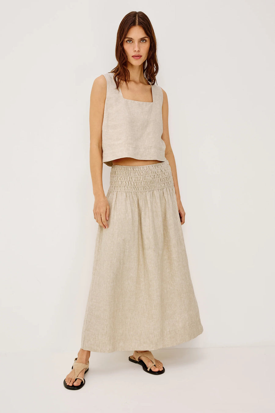 Woman wearing a beige linen midi skirt with a smocked elastic waistband, front