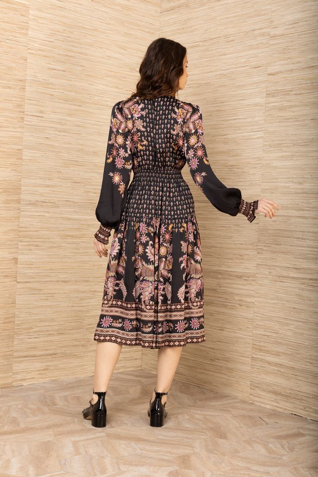 Back view of woman wearing a black, pink and brown patterned long sleeve midi dress